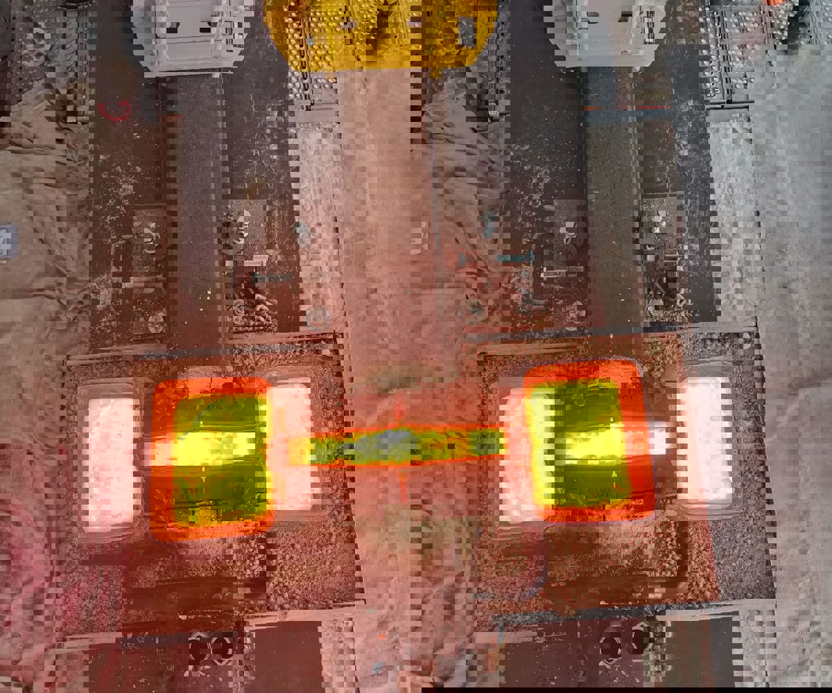 Rautatiekiskon alumiiniterminen hitsaus käynnissä. Sula metalli hohtaa kuumana kiskoliitoksen muotissa.